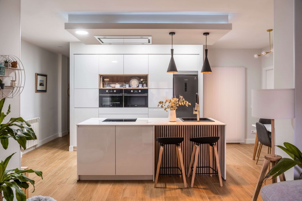 Cocina con isla estratificada blanca y panel de madera