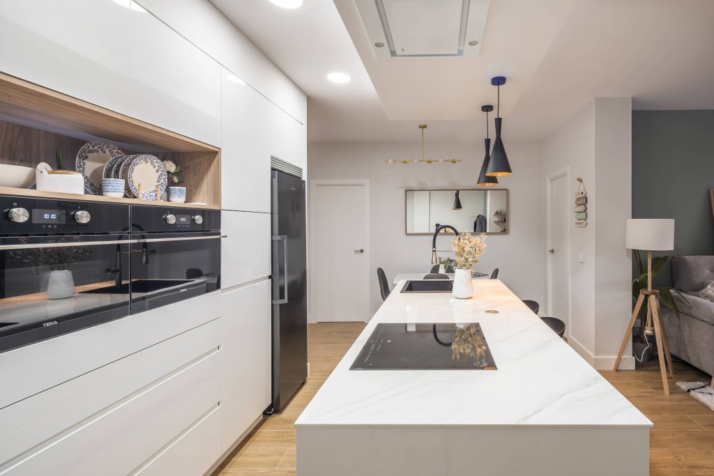 Cocina blanca con isla estratificada y panel de madera