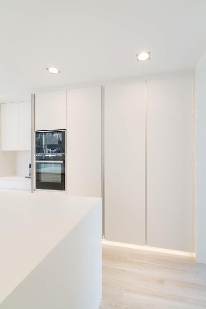 Cocina con isla blanca y concepta detalle luz led blanca