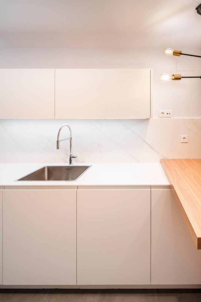 Cocina estratificada blanca con pequeña península de madera