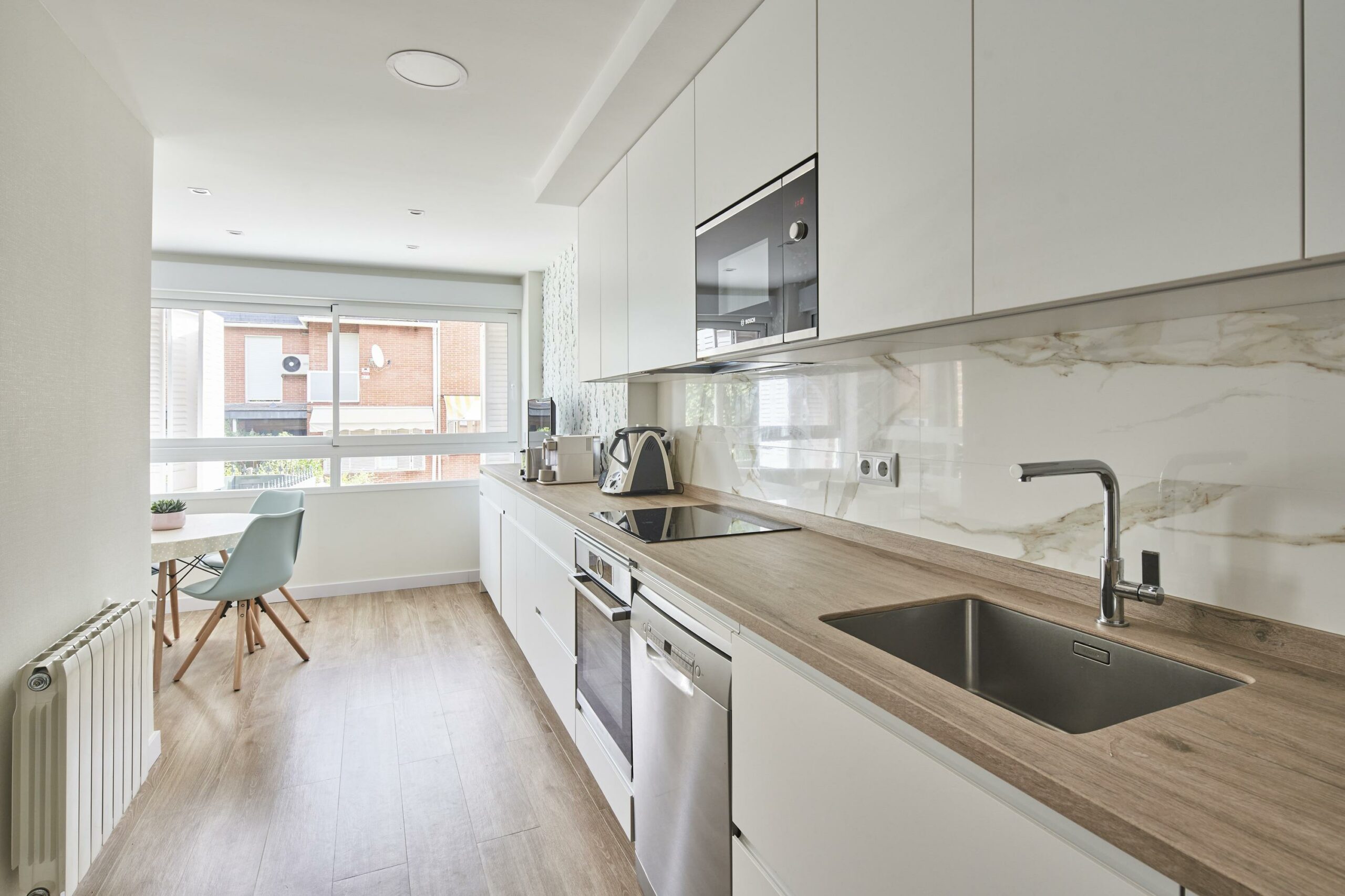 Cocina en dos frentes estratificada blanca con encimera color madera