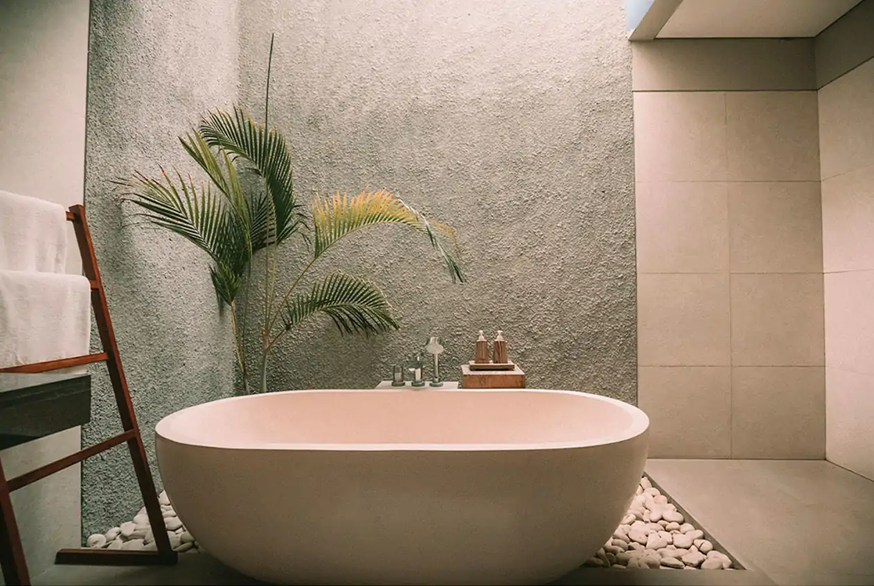 Un baño moderno que invita al relax, donde la armonía entre diseño y naturaleza crea el equilibrio perfecto. Baño moderno con bañera exenta, pared texturizada y planta decorativa.